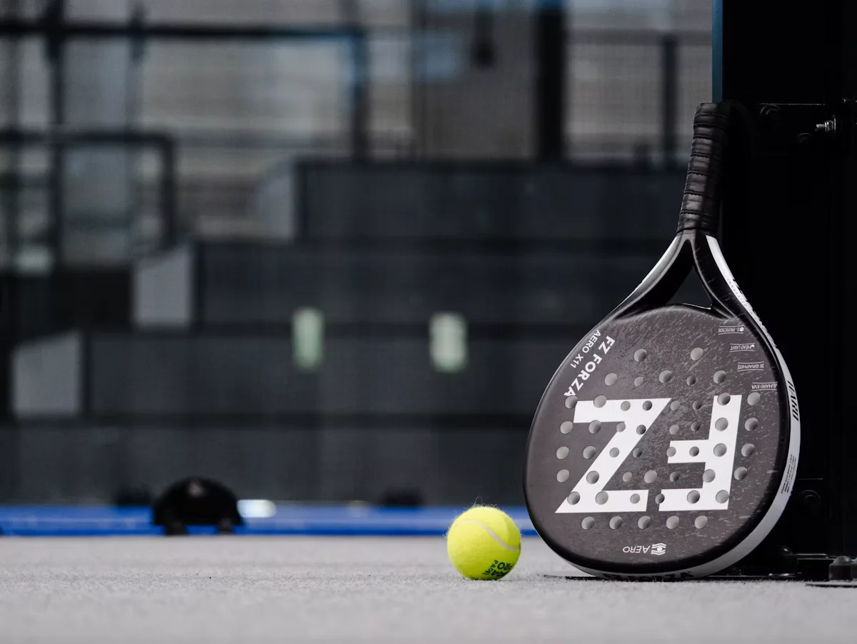 Raquette de padel et balle jaune posées sur un court, illustrant la gestion du rebond