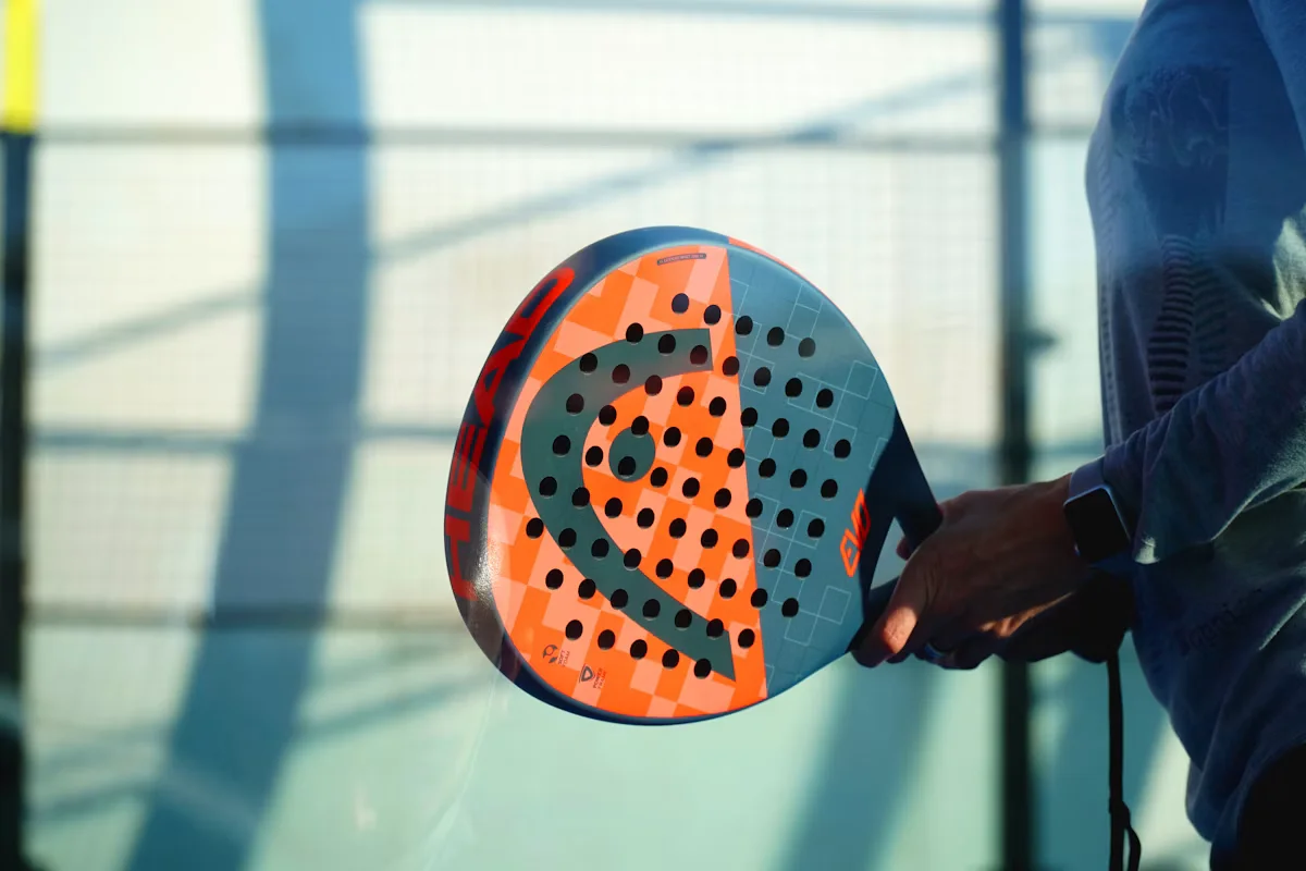 Joueur tenant une raquette de padel orange et bleue en prise continentale