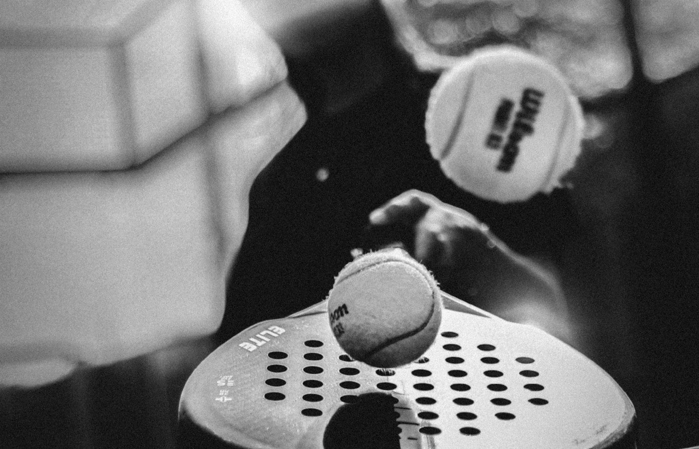Gros plan en noir et blanc d’une raquette de padel percée et d’une balle au moment de l’impact